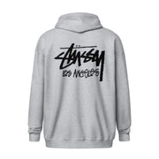 A light gray heather pullover hoodie shown from the back, featuring a large black Stussy Los Angeles logo printed across the upper back.